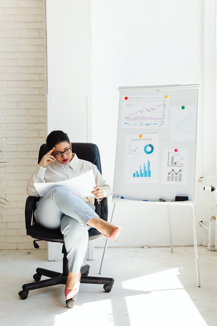 Home Woman analyzing financial charts and graphs in a well-lit office, suggesting business strategy development.